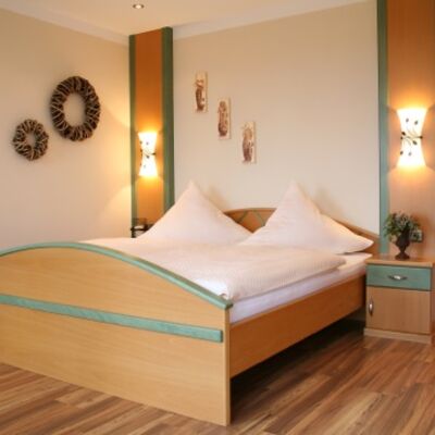 Bild vergrößern: Neben dem Bett aus Holz befindet sich ein passendes Nachtkstchen.