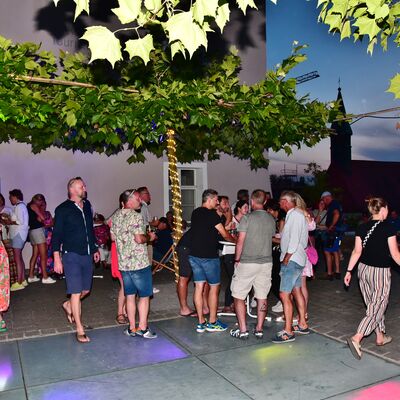 Bild vergrößern: Besucher:innen des Brgerfests stehen an Stehtischen auf dem bunt beleuchteten glsernen Tanzboden.