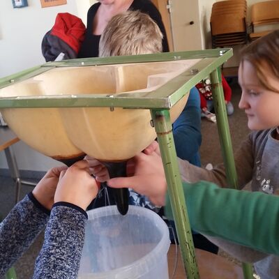 Bild vergrößern: Kindern wird das Melken einer Kuh mittels eines künstlichen Euters erklärt.