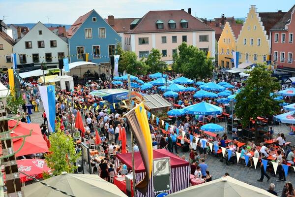 Bild vergrößern: Foto einer Menschenmenge auf dem Marktplatz beim Bürgerfest 2015. Blaue Schirme und bunte Fahnen sind zu sehen.