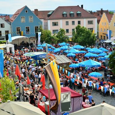 Bild vergrößern: Foto einer Menschenmenge auf dem Marktplatz beim Bürgerfest 2015. Blaue Schirme und bunte Fahnen sind zu sehen.