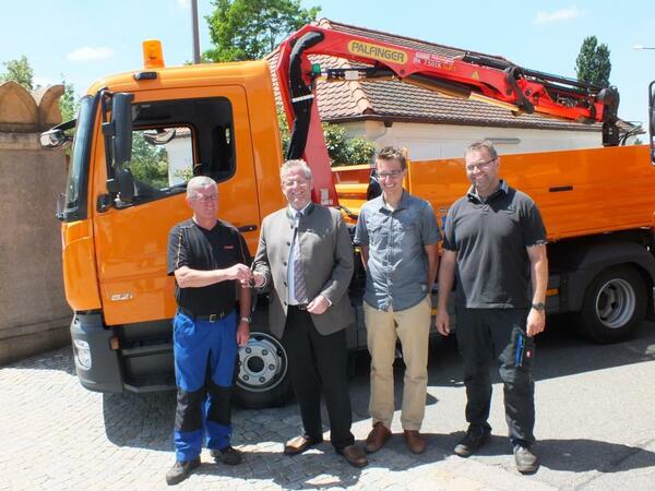 Vier Personen stehen vor einem neuen Lastwagen fr die Mitarbeiter des Bauhofes.