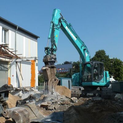 Bild vergrößern: Ein Bagger bricht ein Gebäude ab.