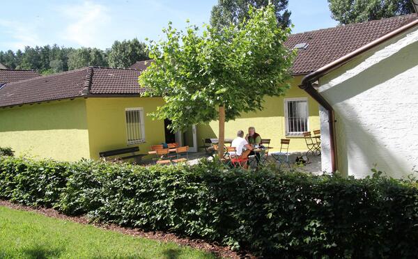 Lesegarten in der Stadtbibliothek. Es stehen viele Tische und St&uuml;hle herum und in der Mitte zeigt sich ein Baum in voller Pracht.