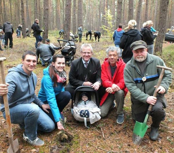Fünf Erwachsene und ein Baby im städtischen Wald, bei der Baumpflanzaktion.