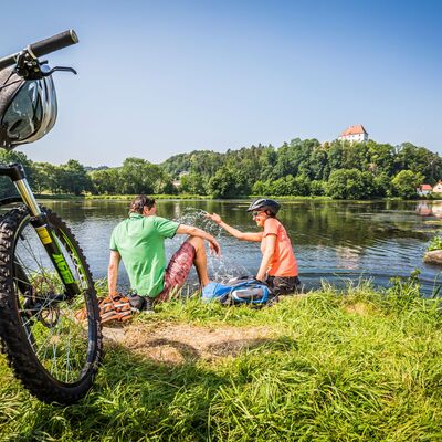 Bild vergrößern: Zwei Radfahrer legen eine Pause am Fluss Regen ein.