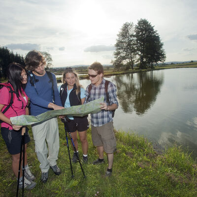 Bild vergrößern: Eine Wandergruppe berprft die Wanderkarte am Weiher.