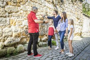 Bild vergrößern: Ein Stadtführer erklärt einer Familie Wissenswertes zur Schwandorfer Stadtmauer.
