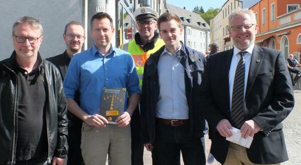 Sechs Personen weisen auf eine  Baustelle in der Innenstadt hin.