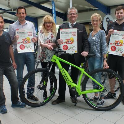 Bild vergrößern: Sechs Personen stehen hinter einem grünen E-Mountainbike Cube Acid Hybrid.