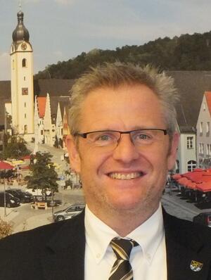 Bild vergrößern: Oberbürgermeister Andreas Feller vor einem Bild mit dem Schwandorfer Marktplatz.