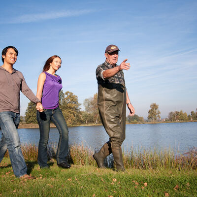 Bild vergrößern: Der Fischer erklärt den Besuchern die Teichanlage.