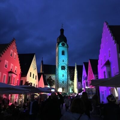 Bild vergrößern: Foto der Marktplatzhäuser Schwandorf, die bei Nacht mit bunten Lichtern bestrahlt  werden.