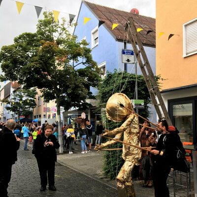Bild vergrößern: Michael Pöllmann wandelt mit seiner goldenen Marionette durch die Breite Straße