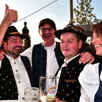 Bild vergrößern: Foto von 4 Menschen des Oberpfälzer Waldvereins in Trachten, lachend. Zwei Biergläser sind im Vordergrund zu sehen.