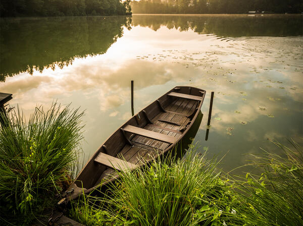 Bild vergrößern: Ein einsames Boot liegt am Rand des Sees.