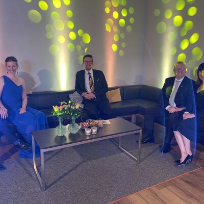 Foto der Moderatoren Anna Theuerl, Johannes Lohrer und zwei weiteren Personen auf dem Sofa in der Loung des Tanzballs. Es gibt Lichtdekoration.