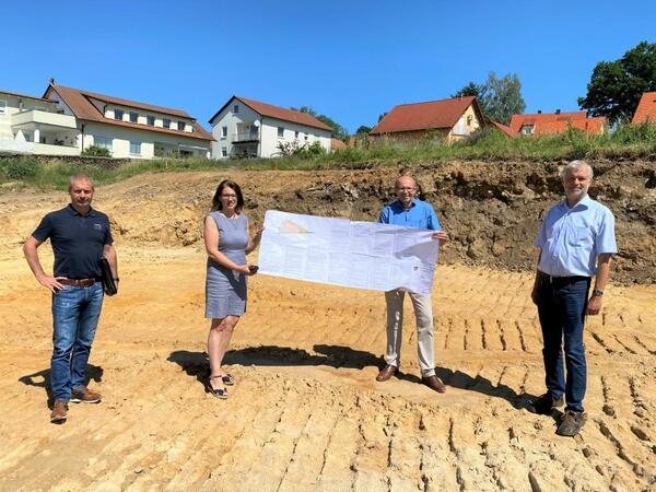 Bild vergrößern: Vier Personen stellen das Baugebiet "Schlossacker" vor. Zwei von ihnen halten einen Bauplan.