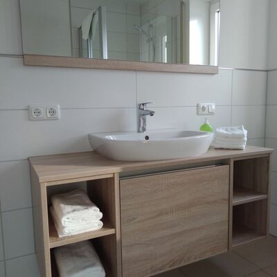 Bild vergrößern: Waschbecken mit einer Holzfront und passenden Spiegel.