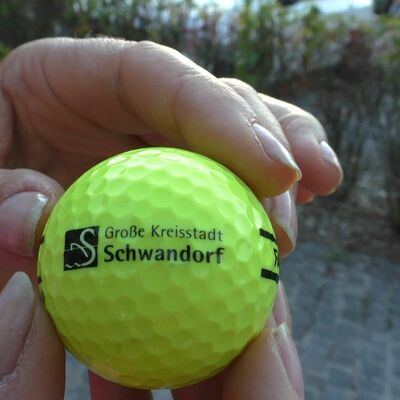 Bild vergrößern: Ein gelber Golfball mit dem Logo der Stadt Schwandorf darauf.