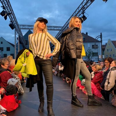 Bild vergrößern: Zwei Frauen auf einem Laufsteg bei einer Modenschau.