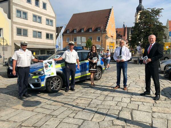 Fnf Personen auf dem Schwandorfer Marktplatz vor einem Polizeiauto.