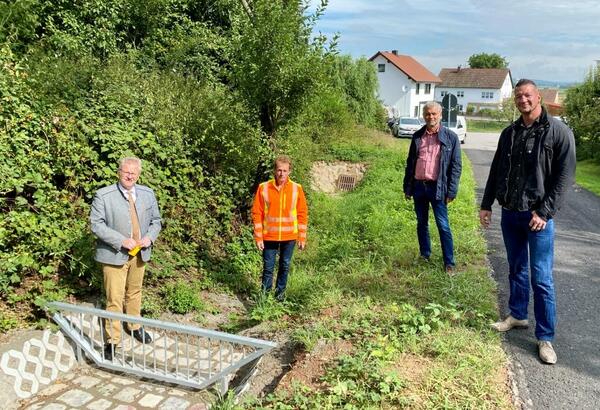 Vier Personen vor einem Schutzgitter, das berflutungen vermeiden soll.