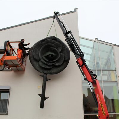 Bild vergrößern: Mitarbeiter der Firma Zinnbauer und des städtischen Bauhofs montieren die Kupfer-Rose an der Außenfassade des Elisabethenheims.