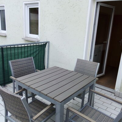 Bild vergrößern: Am Balkon befindet sich ein grauer Tisch mit vier passenden Stühlen.