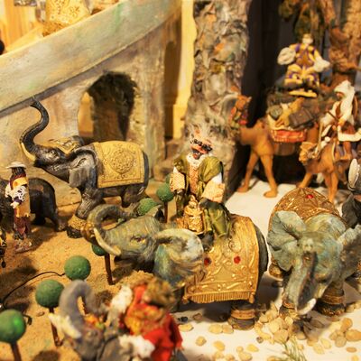 Bild vergrößern: Figuren aus der Krippe "Fünf Epiphanien als barockes Welttheater". Es stehen drei Elefanten herum. Auf einen der drei Elefanten sitzt eine Figur mit grünem Gewand.