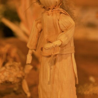 Bild vergrößern: Nahaufnahme einer aus Maisblättern gefertigten Figur. Weiblich. Lange Haare. Eine Hand nach vorne ausgestreckt.
