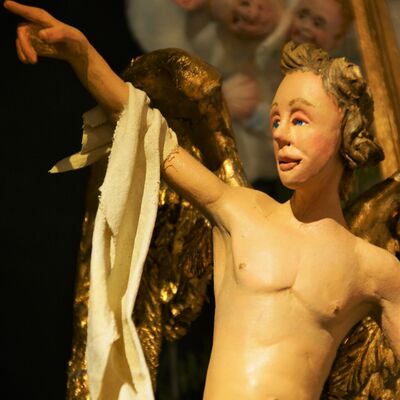 Bild vergrößern: Der Engel aus der Krippe "Hirtenverkündigung" in Nahaufnahme. 
Er hat goldbraunes lockiges Haar.