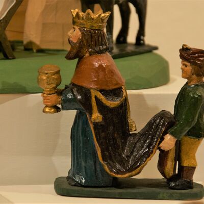 Bild vergrößern: Eine männliche Figur hält ein prachtvolles Trinkgefäß in der Hand. Die Figur ist mit einem langen Umhang gekleidet und trägt eine Krone. Eine kleinere, nicht so prachtvoll gekleidete Figur steht hinter dem König und hält sein langes Gewand, damit dieses nicht am Boden schleift.