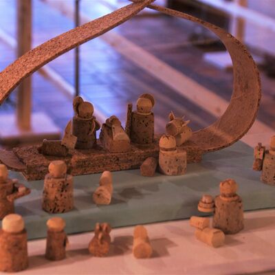 Bild vergrößern: Viele, aus Kork gefertigte Figuren sind vor dem Jesuskind angeordnet. Ein aus Kork gefertigter BOgen stellt den Stall dar. Eine Figur vor dem Stall hat eine Krone auf. Schaafe sind zwischen den Figuren abgebildet.