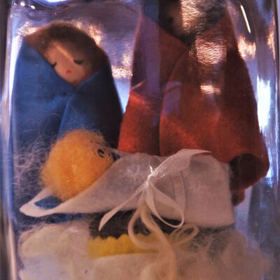 Bild vergrößern: In einem großen Einmachglas sind 3 gefilzte Figuren zu sehen. Eine Frau ein Mann und vor den beiden Figuren ein Baby, eingewickelt in einer Decke. Die beiden Figuren im Hintergrund haben ebenfalls Decken umhängen.