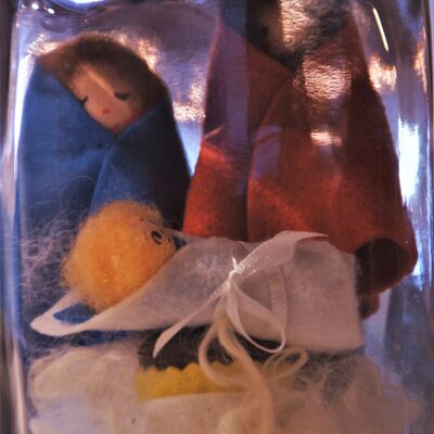 Bild vergrößern: In einem groen Einmachglas sind 3 gefilzte Figuren zu sehen. Eine Frau ein Mann und vor den beiden Figuren ein Baby, eingewickelt in einer Decke. Die beiden Figuren im Hintergrund haben ebenfalls Decken umhngen.