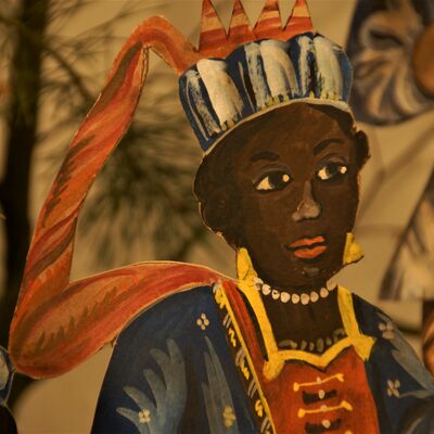 Bild vergrößern: Detailaufnahme einer männlichen Person mit prachtvollem Gewand und Krone auf dem Kopf.