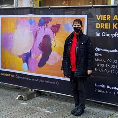 Bild vergrößern: Drei Frauen vor einem Banner mit Bildern.
