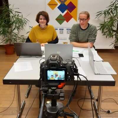 Bild vergrößern: David Bender und Veronika Hofinger vom Centrum Bavaria Bohemia sitzen vor einer Kamera und bereiten sich als Moderatoren auf das Online-Seminar vor.