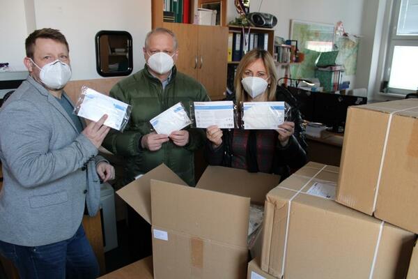 Drei Personen nehmen mehrere Pakete mit FFP2 Masken in Empfang.
