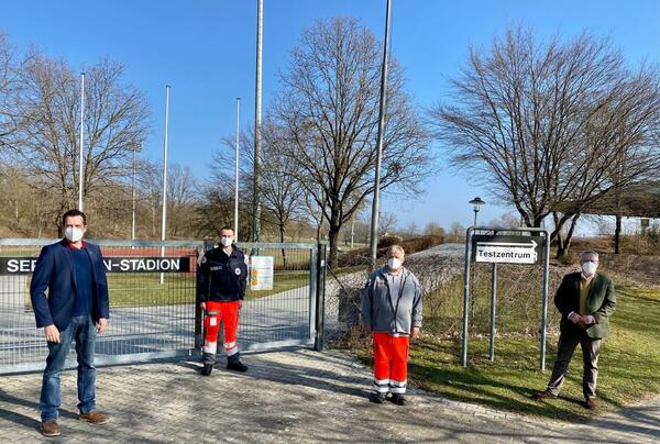 Bild vergrößern: Vier Personen stehen vor einem Tor eines Fußballstadions.