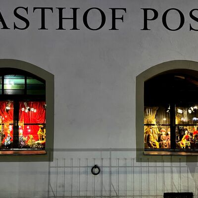 Bild vergrößern: die ehemalige Gaststätte "Zur Post" von außen, bei nacht mit den geschmückten Fenstern.