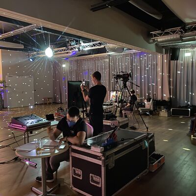 Foto: Zwei Personen arbeiten mit den technischen Geräten beim Stadtball. Der Raum ist mit einer Lichtshow dekoriert.