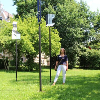 Bild vergrößern: Eine Gästeführerin erklärt ein Kunstwerk im Park des Oberpfälzer Künstlerhauses.