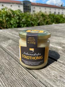 Bild vergrößern: Ein Glas Honig mit der Aufschrift auf einen braunen Etikett "Schwandorfer Stadthonig"-250g. Verschlossen mit einem goldenen Deckel.