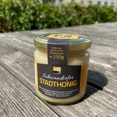 Ein Glas Honig mit der Aufschrift auf einen braunen Etikett "Schwandorfer Stadthonig"-250g. Verschlossen mit einem goldenen Deckel.