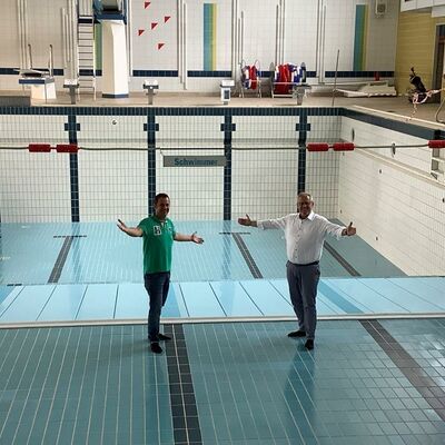 Bild vergrößern: Zwei Personen in einem Hallenbad im Schwimmbecken ohne Wasser.