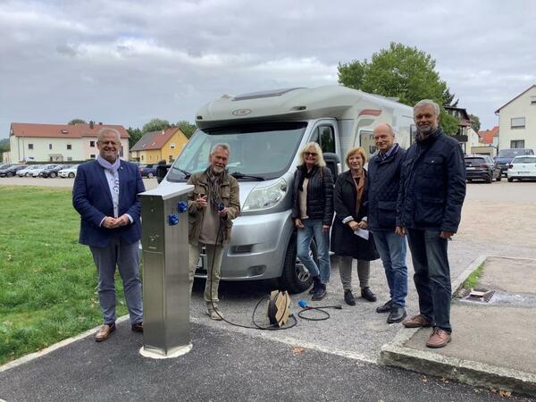 Bild vergrößern: Sechs Personen bei Inbetriebnahme einer Stromladesäule für Wohnmobile.
