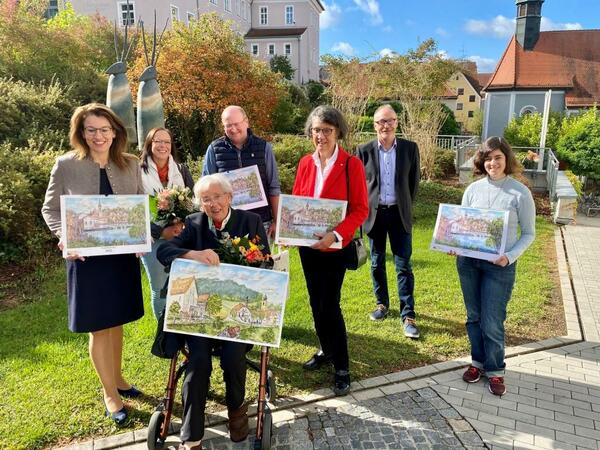 Sieben Personen zeigen einen Kalender der Stadt.