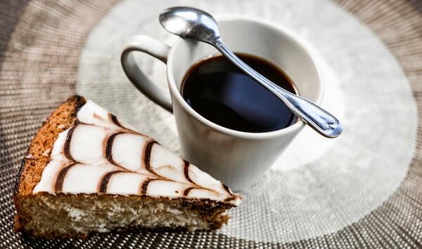 Ein Stück Kuchen und eine Tasse Kaffee mit Kaffeelöffel.